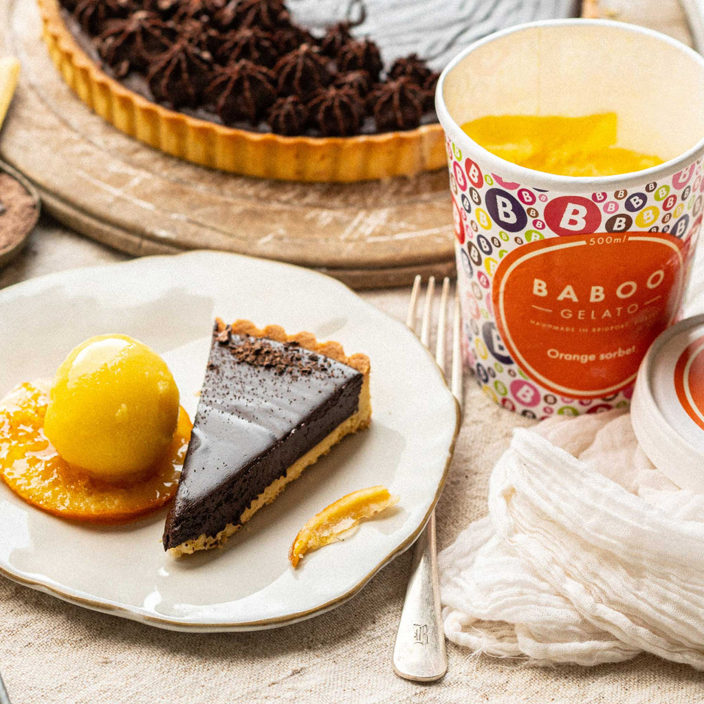 Chocolate tart with scoop of orange sorbet and tart in the background